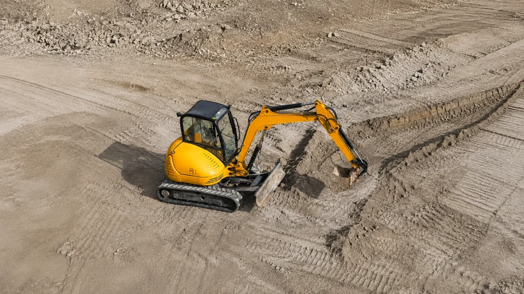 Yellow excavator operating on a construction site with hydraulic bucket and tracked undercarriage